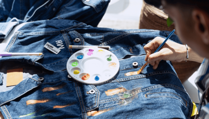 Persona pintando una chaqueta de denim con pinturas