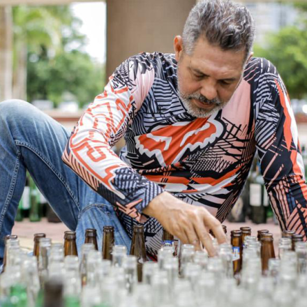Hombre reuniendo botellas para muestra artística