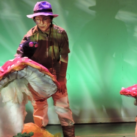 mujer con títeres de hongos gigantes