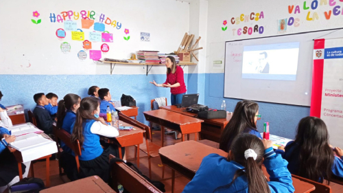 profesora dictando una clase a un grupo de niñas y niños