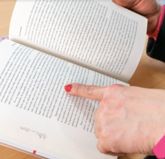 Mano de mujer señalando un párrafo de un libro
